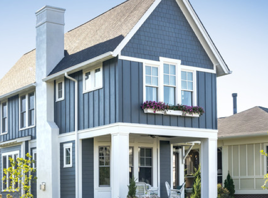 Two-story blue house with white trim, enhanced by Painting Plus, featuring a porch with chairs and a flower box under the upstairs window. Surrounded by a well-kept lawn and garden, it sits under a clear blue sky. Two-story blue house with white trim, enhanced by Painting Plus, featuring a porch with chairs and a flower box under the upstairs window. Surrounded by a well-kept lawn and garden, it sits under a clear blue sky.